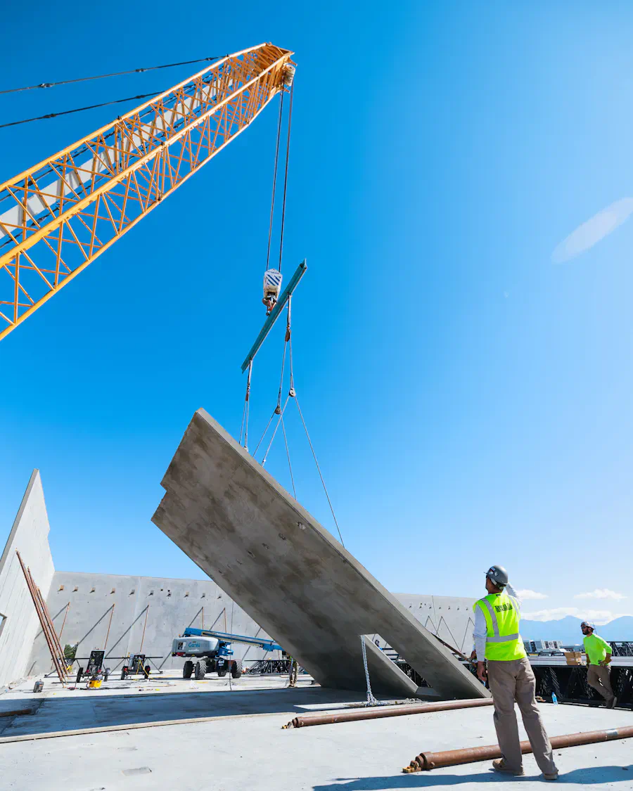Supervisor con casco observa cómo una grúa iza un panel de hormigón